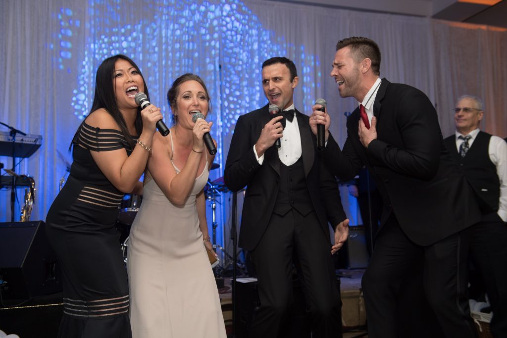 groom singing on stage with his friends