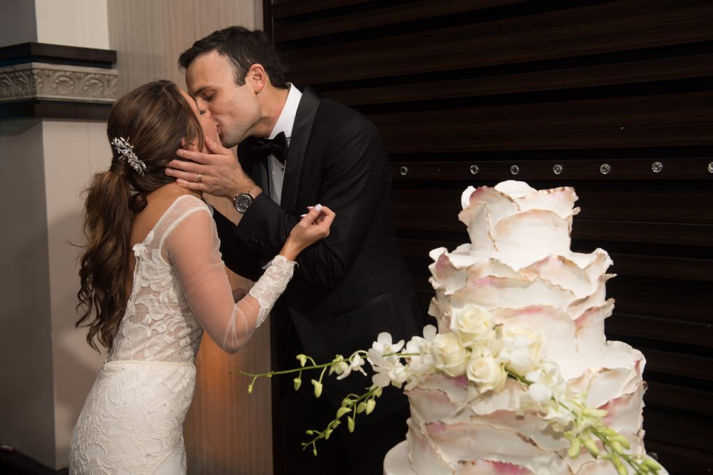 bride and groom kiss by wedding cake