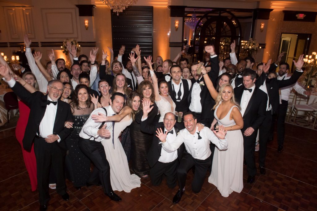 bride and groom wave goodbye with all their friends and family