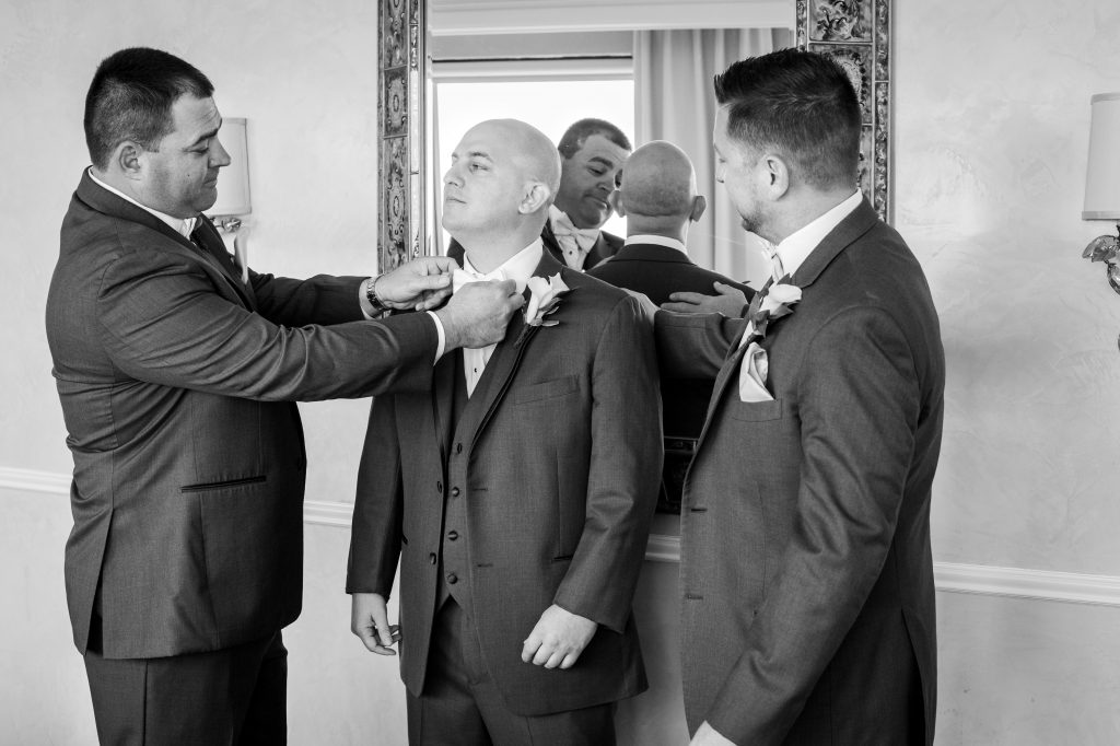 groomsman adjusting grooms tie