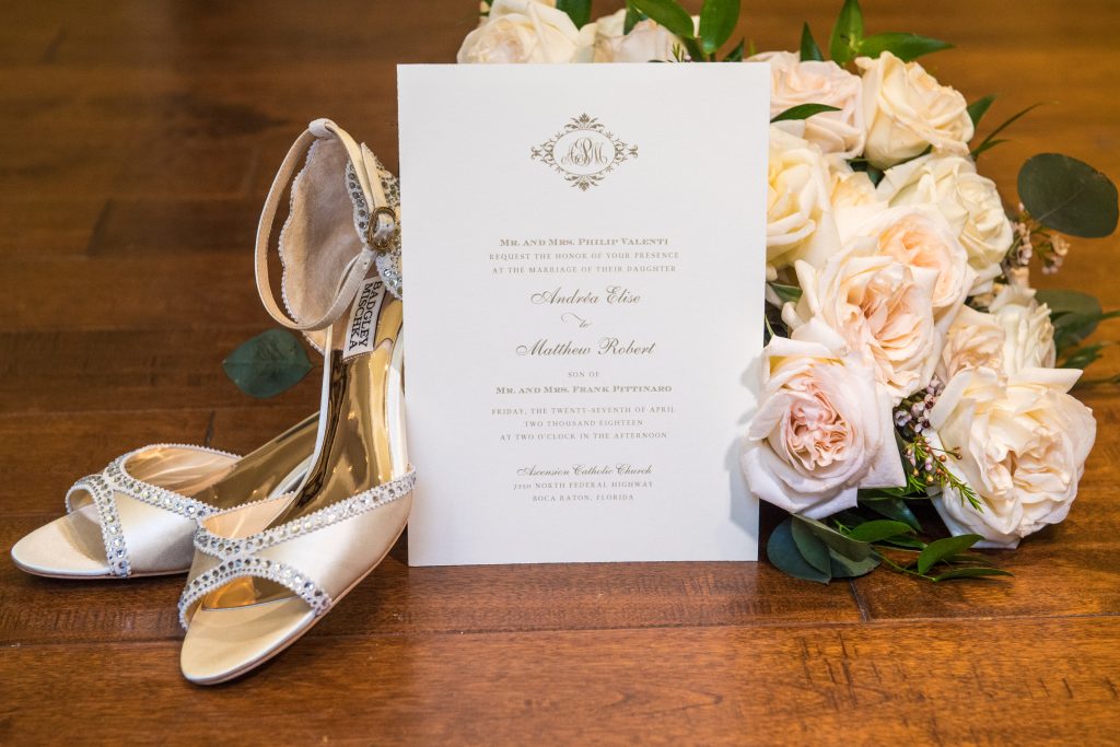 bride's shoes with flowers and invitation