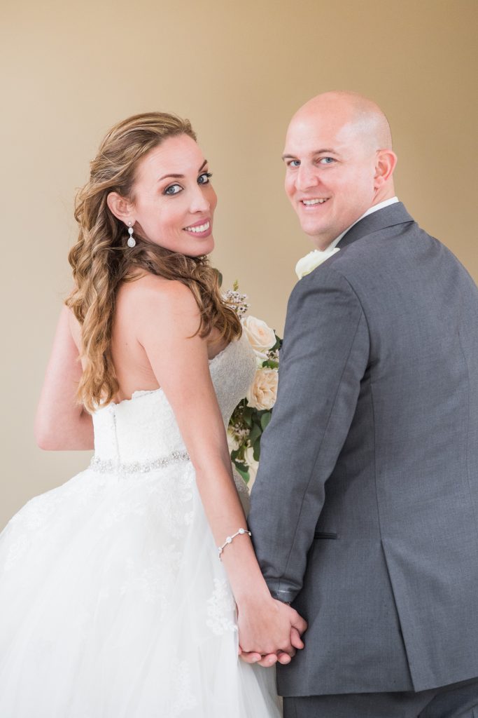 bride and groom holding hands looking back