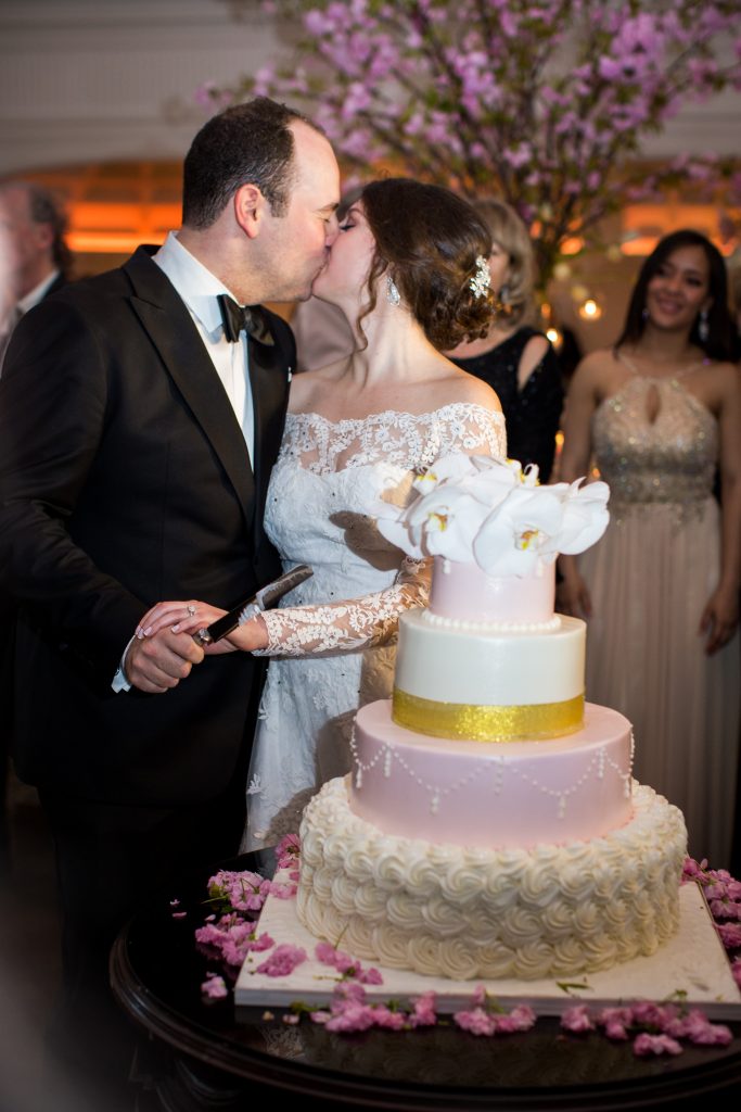 bride and groom kiss by wedding cake