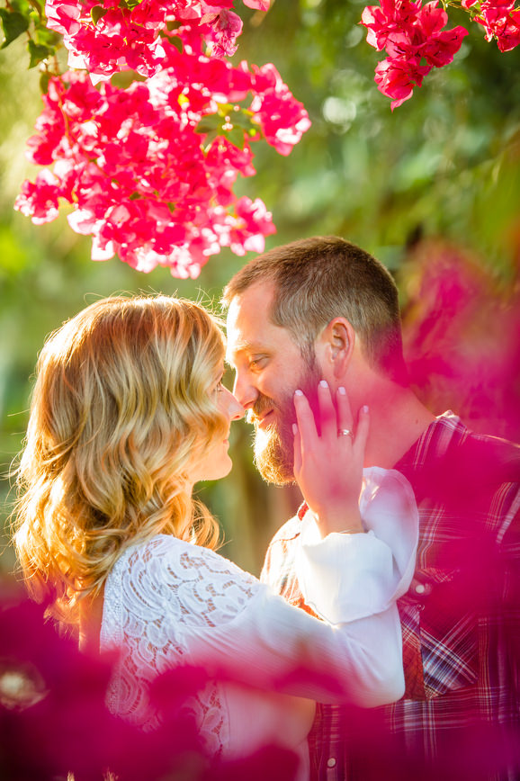 Engaged couple about to kiss through flowers