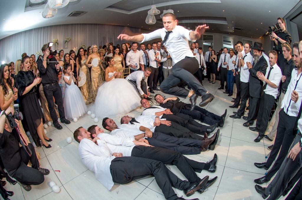 Groom jumping over groomsmen