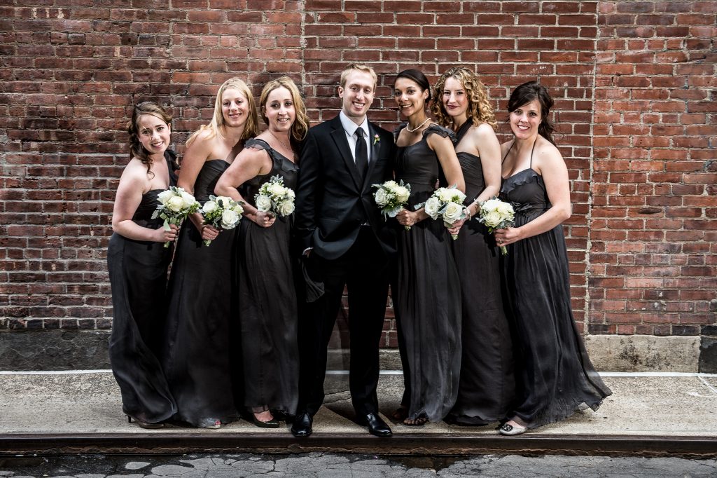 Groom standing with bridesmaids
