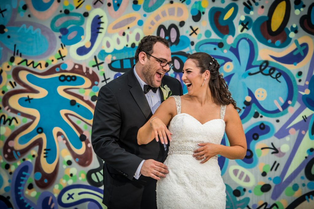 Bride and Groom laughing in front of grafitti wall
