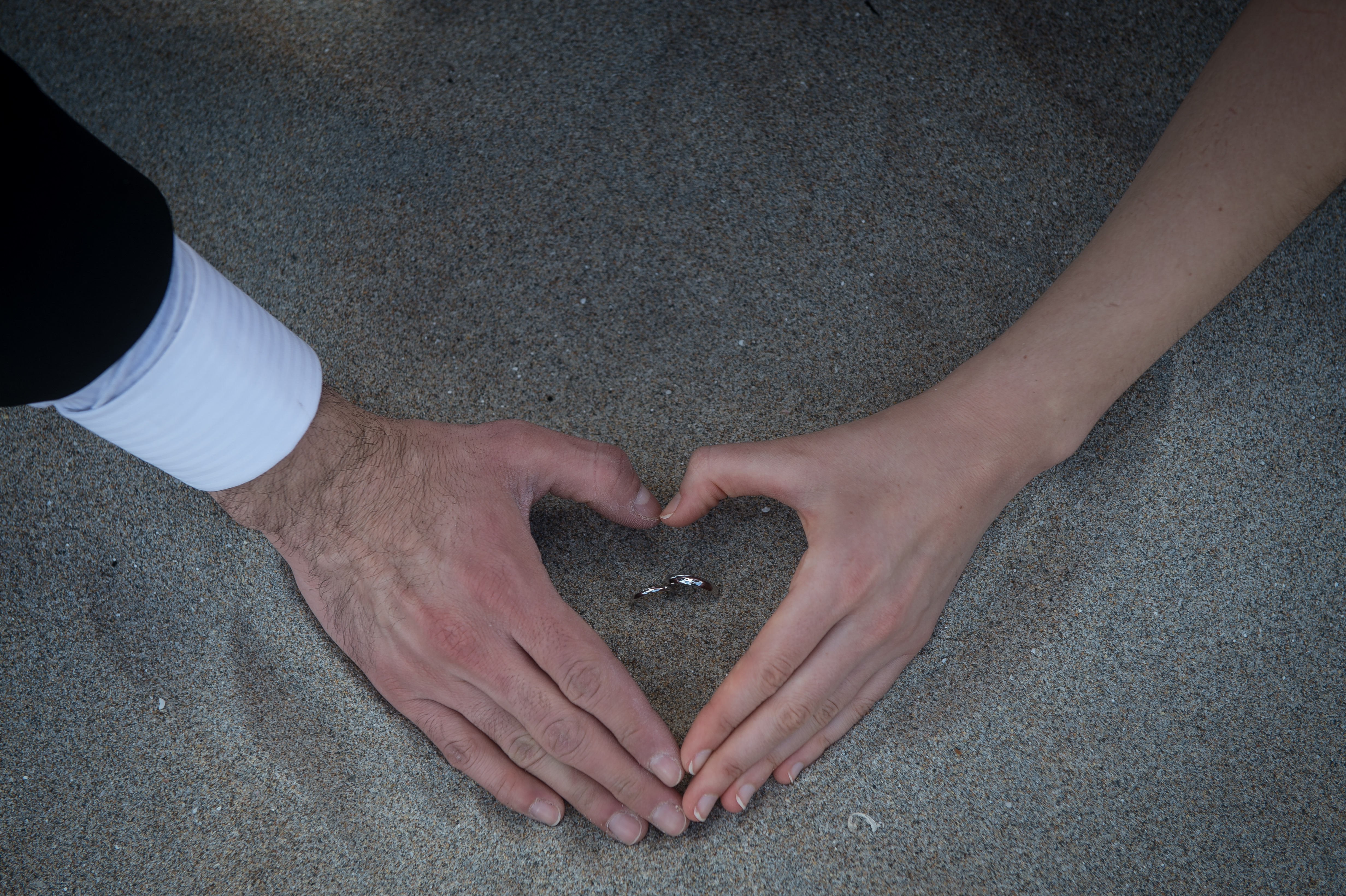 Engaged hand heart in sand with ring