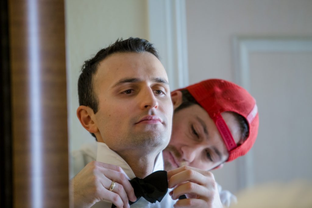 Best man helping groom with bowtie